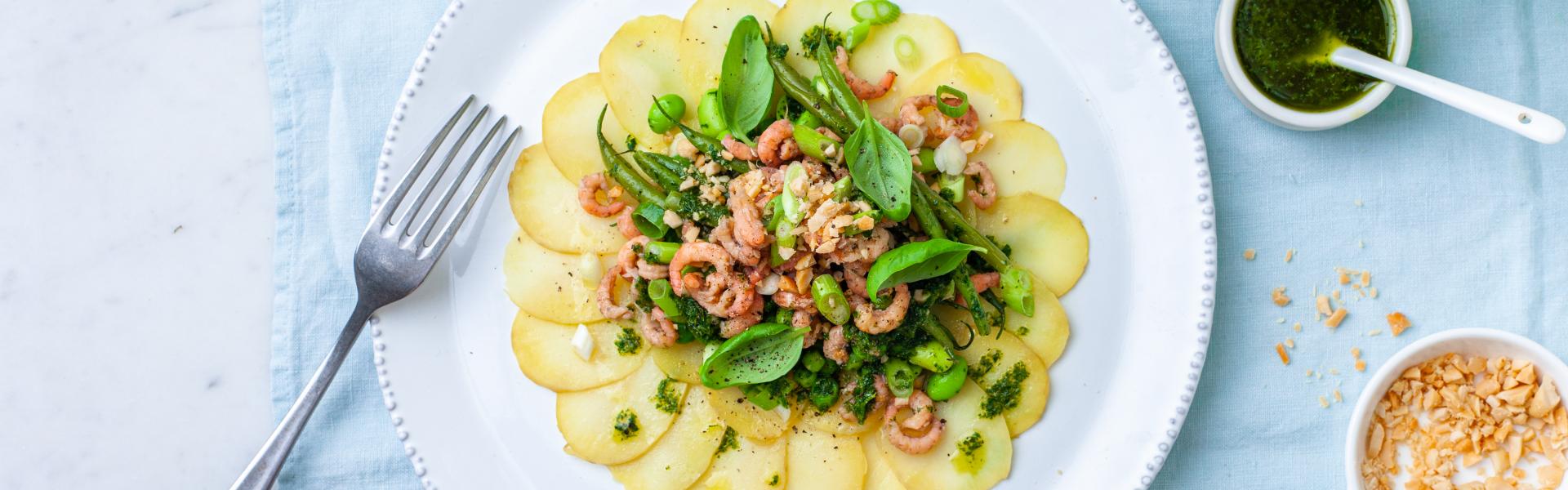 Aardappelcarpaccio met een groene sla en verse grijze garnalen